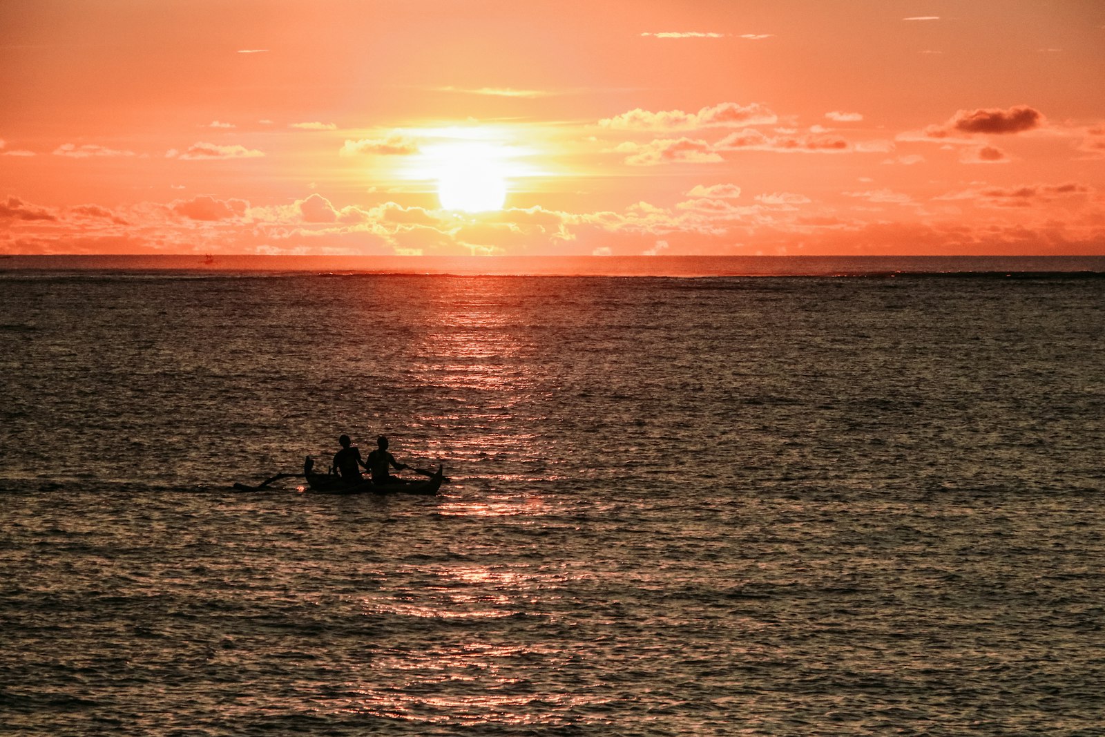 silhouette of two people near boat during sunset
