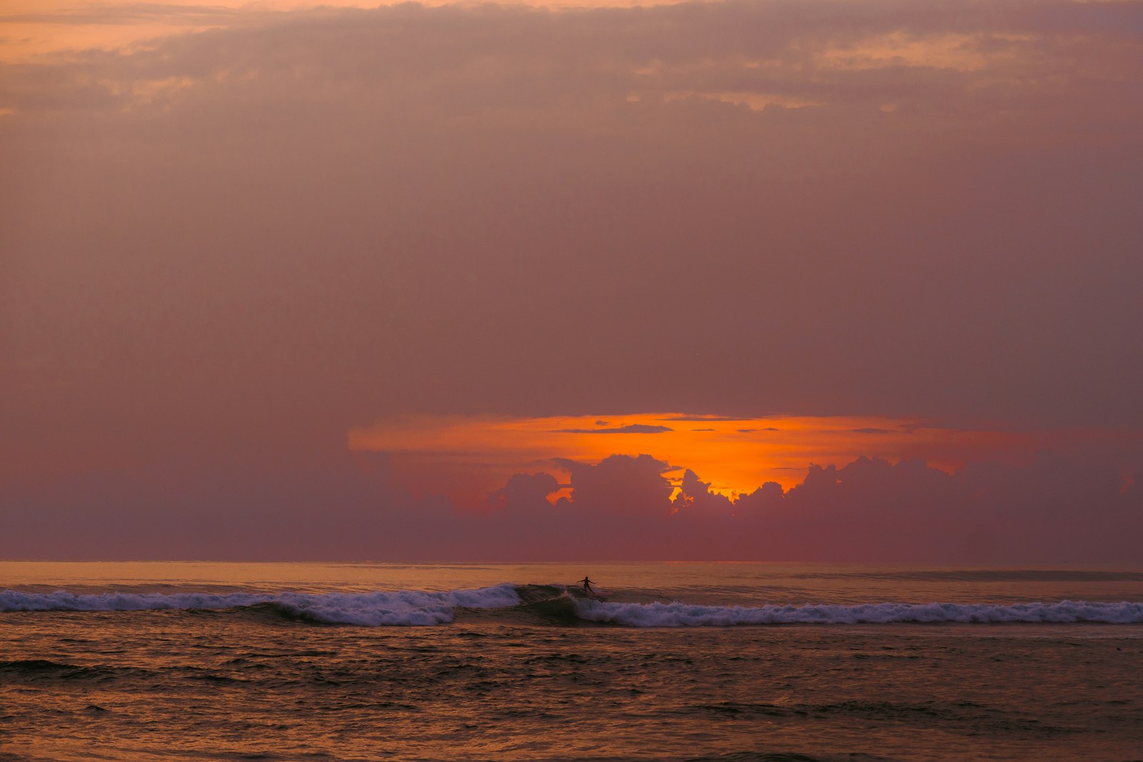 Sunset over the ocean, with a wave.