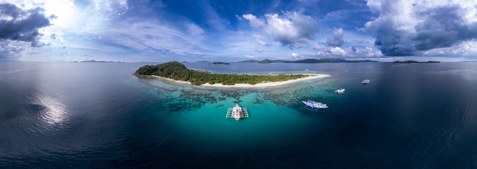 Tropical island with boats in clear turquoise water.
