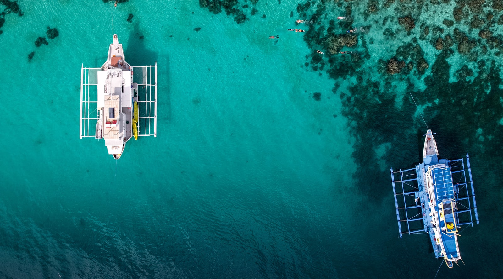 Two boats float on clear turquoise ocean water.